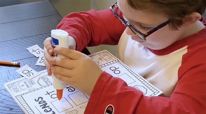 Child with glasses glueing on paper
